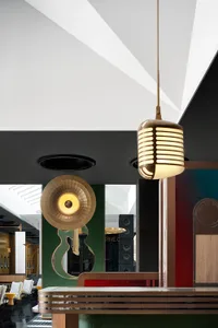 A modern hotel reception counter with a brass and leather finish, featuring a retro microphone light fixture and a guitar-sha