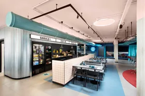 An industrial-style cafe with metal pipes, glass surfaces, and concrete flooring.