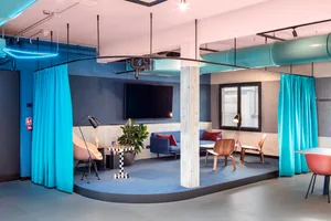 A modern industrial office lounge features concrete, glass, and fabric materials.