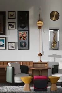 Modern living room featuring wooden furniture, colorful stools, and a wall gallery with musical memorabilia.