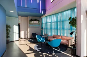 A modern lobby with blue fabric furniture, glass walls, and metallic accents.