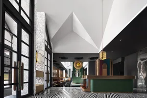 A modern lobby with marble walls, glass elements, metal accents, and wooden furniture.