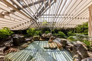 A modern spa interior with a glass roof, surrounded by greenery and natural elements.