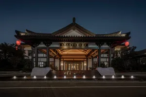 A traditional Chinese hotel entrance with brick and marble columns, illuminated by lanterns and modern lighting.