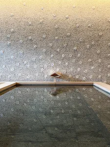 A minimalist pool with a concrete texture and a small wooden structure in the center.