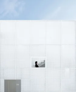 A minimalist building facade with a white perforated metal design.