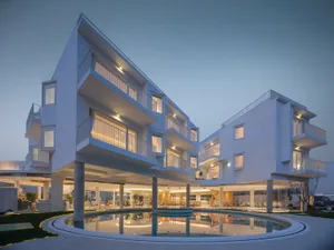 Modern apartments featuring glass and concrete architecture with a central pool area.