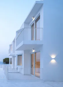 A modern building exterior with white concrete walls and a flat roof.