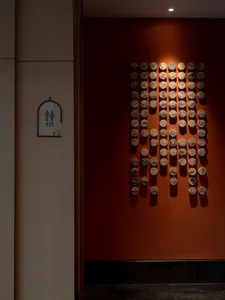 Modern interior space featuring decorative ceramic tiles on a deep red wall, with concrete and terrazzo elements