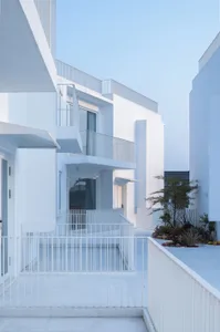 Modern residential exterior with concrete walls and white railings.