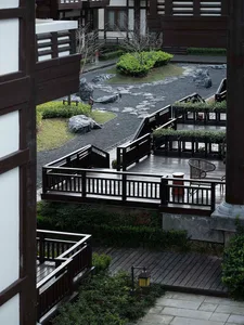 A modern residential garden featuring a wooden pathway surrounded by greenery and rocks.