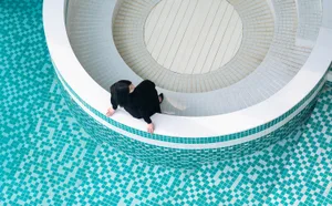 A modern swimming pool with blue tiles and a white circular structure.