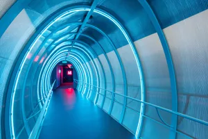 A futuristic tunnel constructed with metallic materials and illuminated internally.