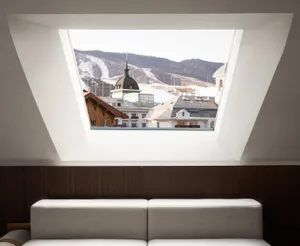 A white sofa with a view of a snowy cityscape through a large window.