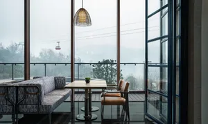 Modern metallic restaurant interior with bar seating, large windows, and mountain view.