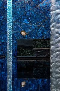 A modern hotel swimming pool with blue tiles and underwater reflections on concrete walls.
