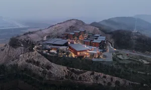 A resort with modern architecture, featuring wooden structures with glass windows at dusk.