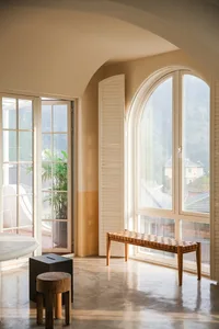 Modern living room featuring glass walls and a large arched window.