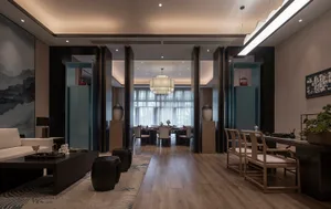 A modern living and dining room interior with wooden flooring, glass elements, and fabric seating.
