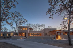 Modern residential exterior with concrete walls and warm interior lights.