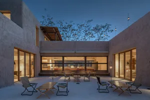 A modern residential patio made of concrete with outdoor furniture and lights.