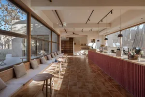 Modern cafe interior featuring a seating area with pillows, a counter, and a barista station.