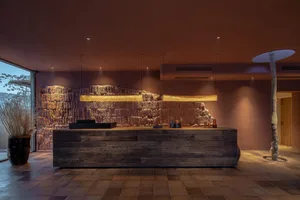Industrial-style reception desk made of wood with a rock wall background.