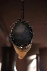 Metallic industrial-style pendant light with leather straps and a black spherical shade.
