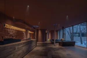 A spacious, industrial-style lobby with concrete walls and floor, featuring modern furniture and a reception desk.