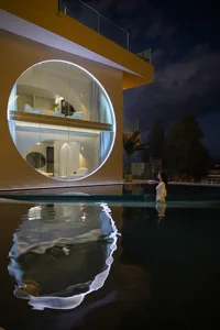 A modern poolside lounge featuring large circular glass windows at night.