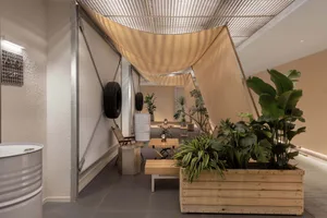 Industrial-style cafe interior featuring wooden planters, concrete furniture, and exposed concrete walls.
