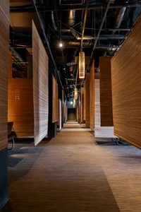 A dimly lit, industrial-style corridor adorned with wooden panels and pendant lights.