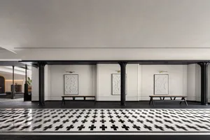 Industrial style lobby with concrete columns, white walls with abstract art, and a patterned black and white floor.