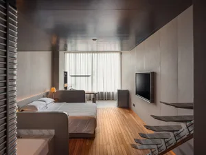 Modern bedroom with minimalist design, featuring a sleek metal bed frame and wooden flooring.
