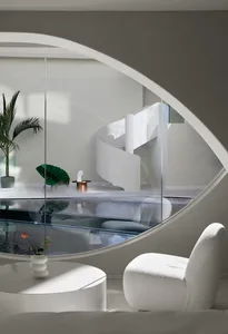 Modern minimalist interior with a glass spiral staircase and large, curved window overlooking a pool.