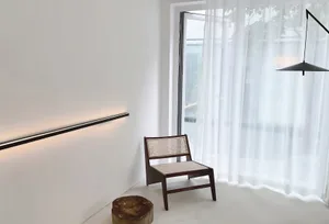 A minimalist interior featuring a large glass window and wooden furniture.