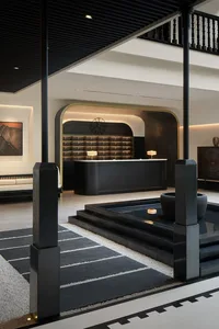 Modern, minimalist lobby reception area with a concrete material design and a central water feature.