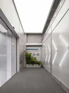 A minimalist office corridor featuring concrete and glass materials.