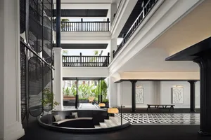 Modern hotel lobby with black glass accents, black glass railings, and stone columns.