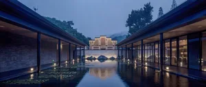 A modern hotel lobby with a water feature, glass walls, and stone walls.