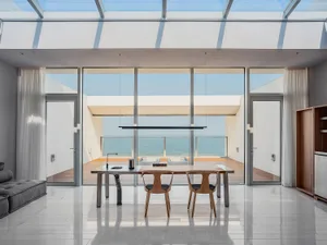 Modern dining room with glass walls overlooking the sea.