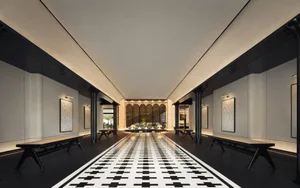 A modern hotel lobby with concrete walls, black sand floor tiles, and a long black and white checkered floor leading to a sea