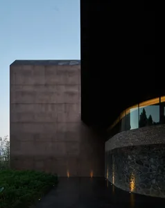 Modern building with dark, metal-clad exterior and curved glass window on the right side.