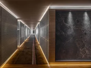 A modern metal corridor with a minimalist design, featuring a long hallway with dark metal walls, a light-colored floor, and 