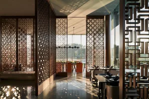 A modern restaurant interior featuring metallic wall screens and wooden tables.