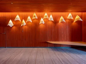 Minimalist modern restaurant interior with wooden paneling and decorative lighting.