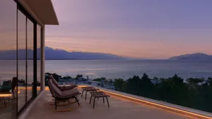 A spacious balcony featuring a luxurious view of the ocean and distant mountains at sunset.