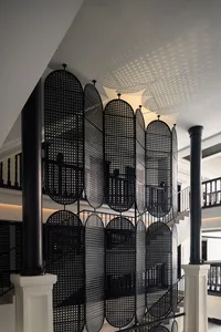 A modern interior staircase with metal railings and an intricate perforated metal panel wall.
