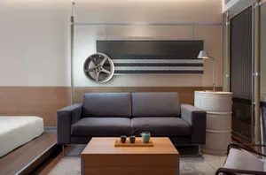 A modern living room featuring concrete flooring, metal wheel art, and minimalist furniture.
