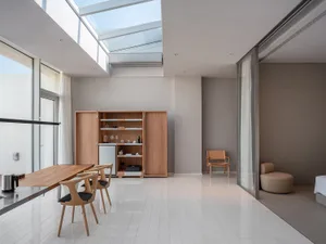 A modern living room with white marble floor, wooden dining table, and minimalist design.